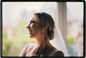 A delicate profile silhouette shows a veil and dangling earring in soft natural light.