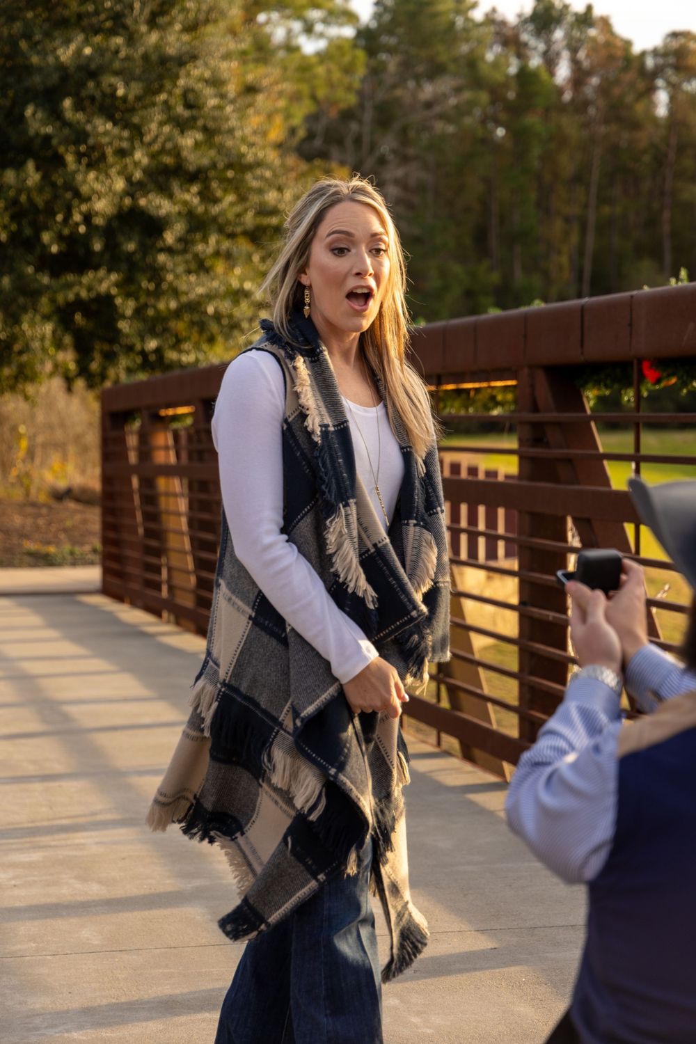 Surprised reaction captured on wooden bridge during sunset proposal moment.