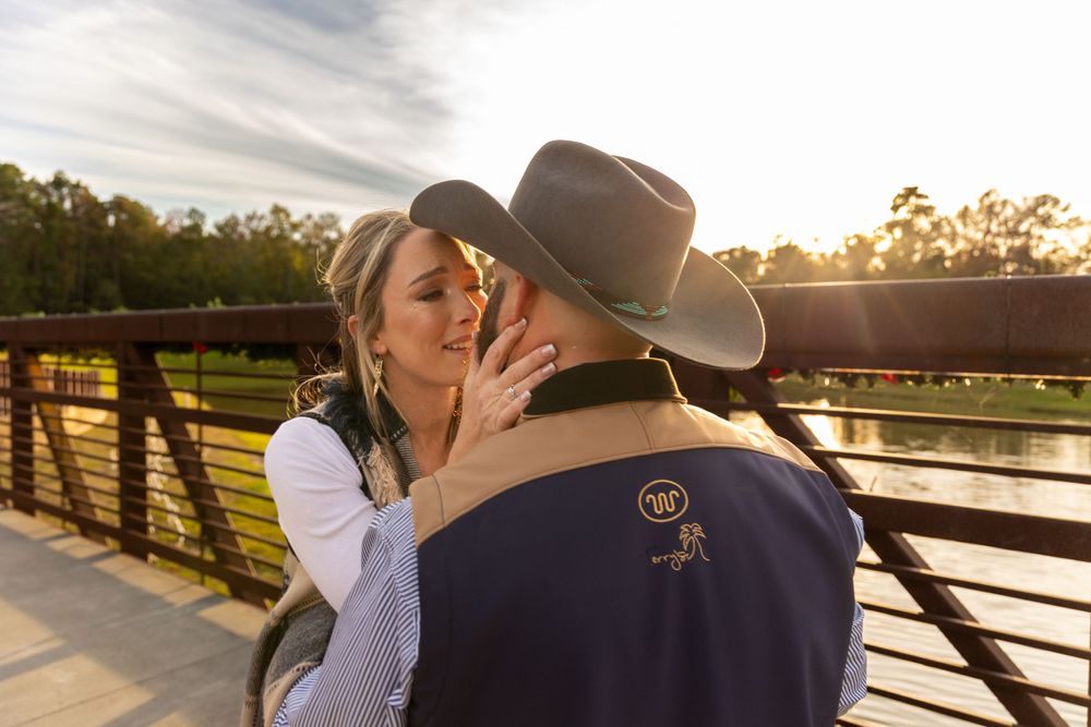 A tender sunset moment between a couple on a bridge.