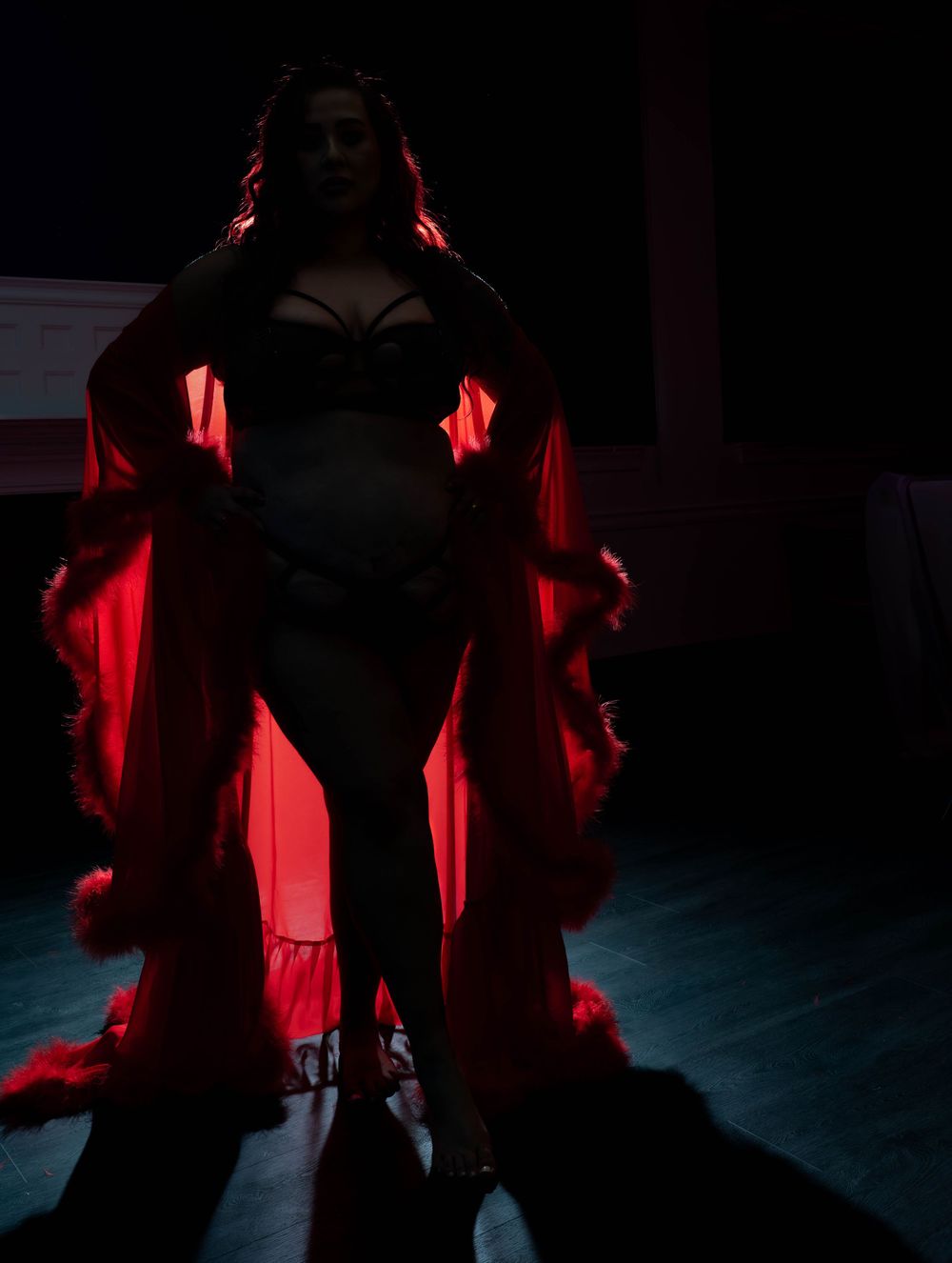 A dramatic silhouette in red lighting stands against a dark background creating an atmospheric theatrical scene.