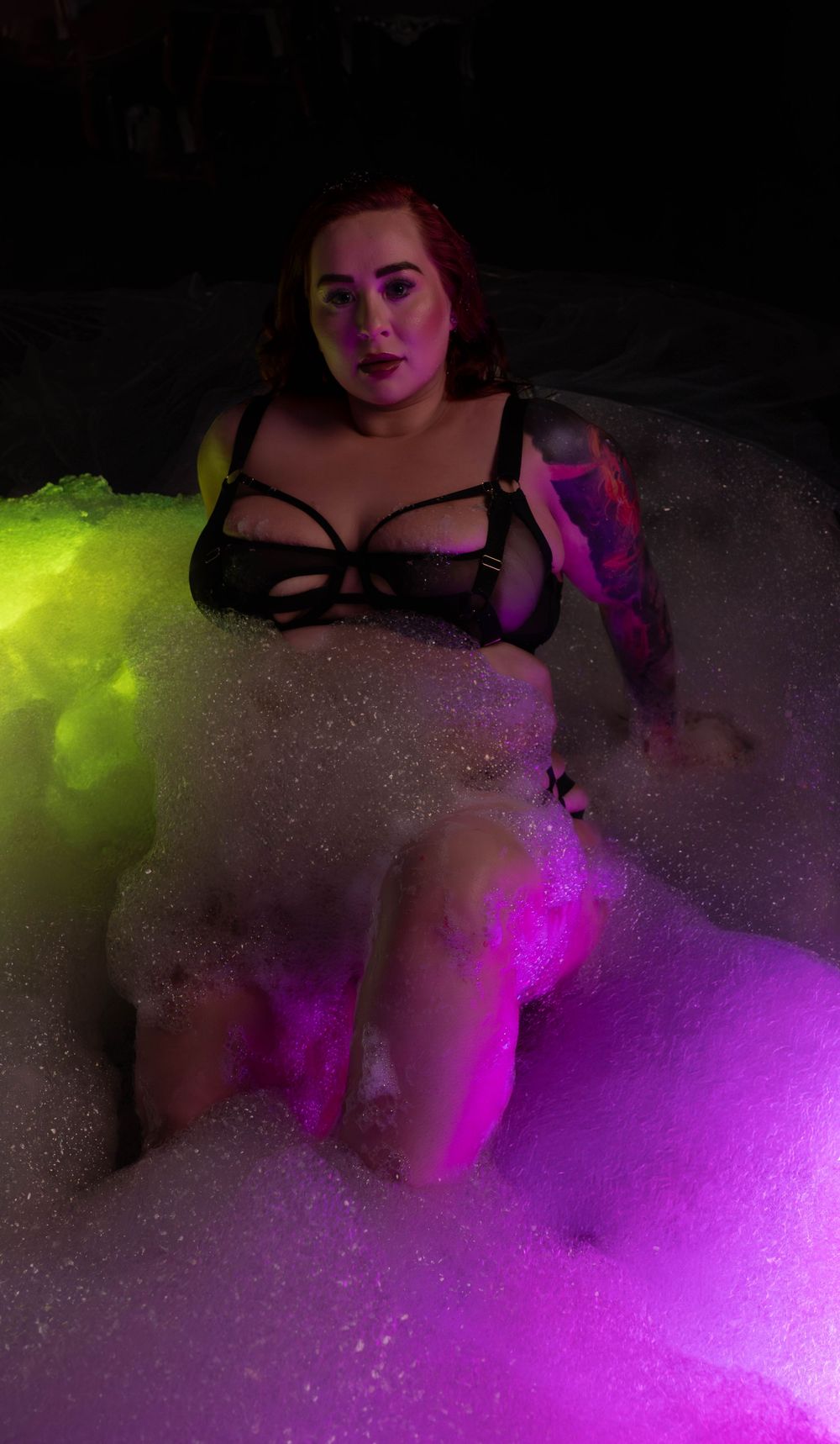 Artistic bathtub scene illuminated by vibrant neon purple and yellow lighting with white bubbles creating a dreamy atmosphere.
