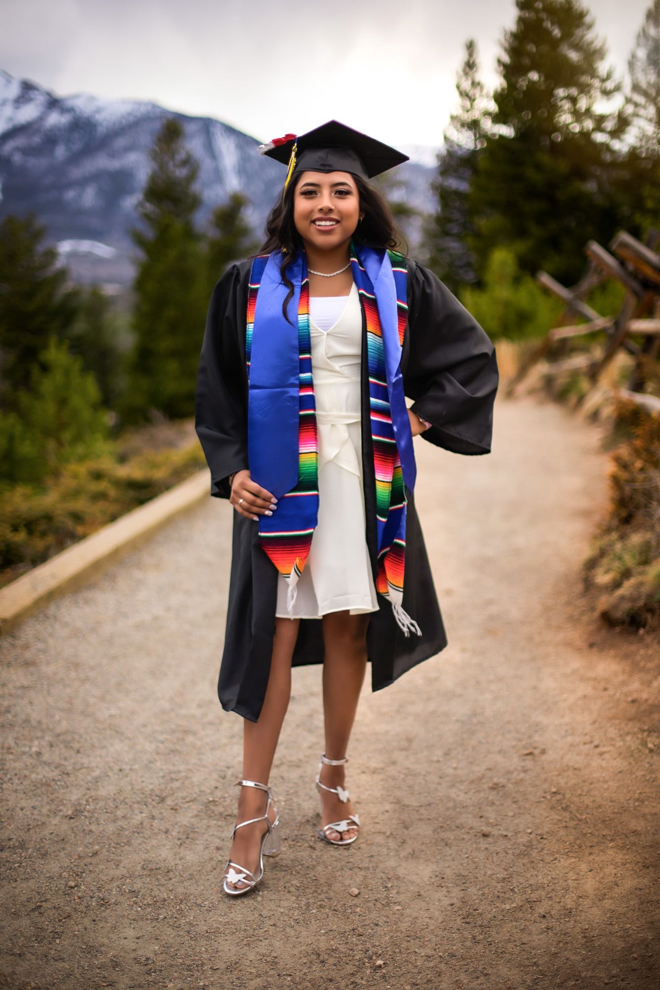 College senior poses in her graduation regalia and smiles at camera