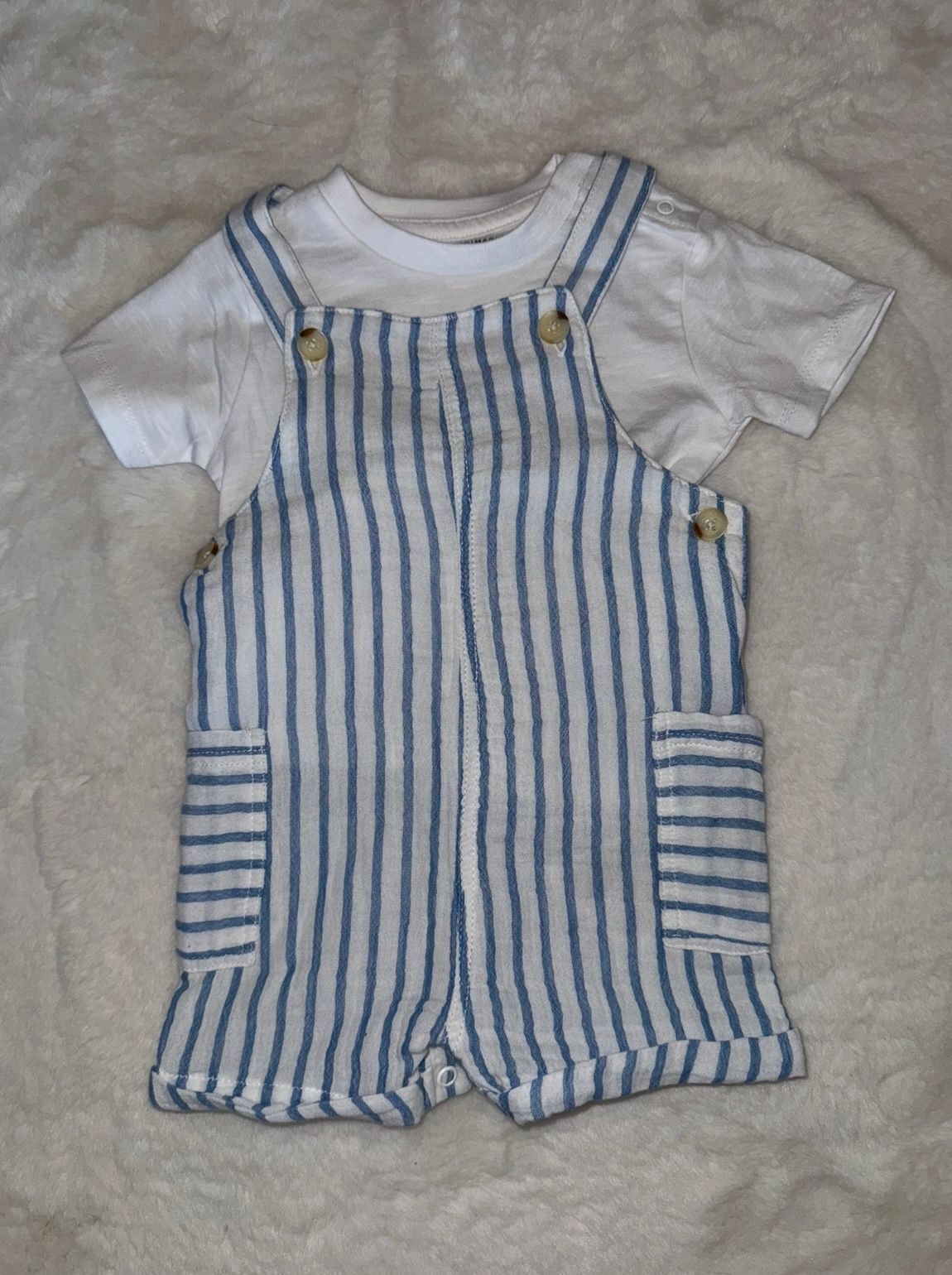 Blue and white striped baby romper with front pockets.