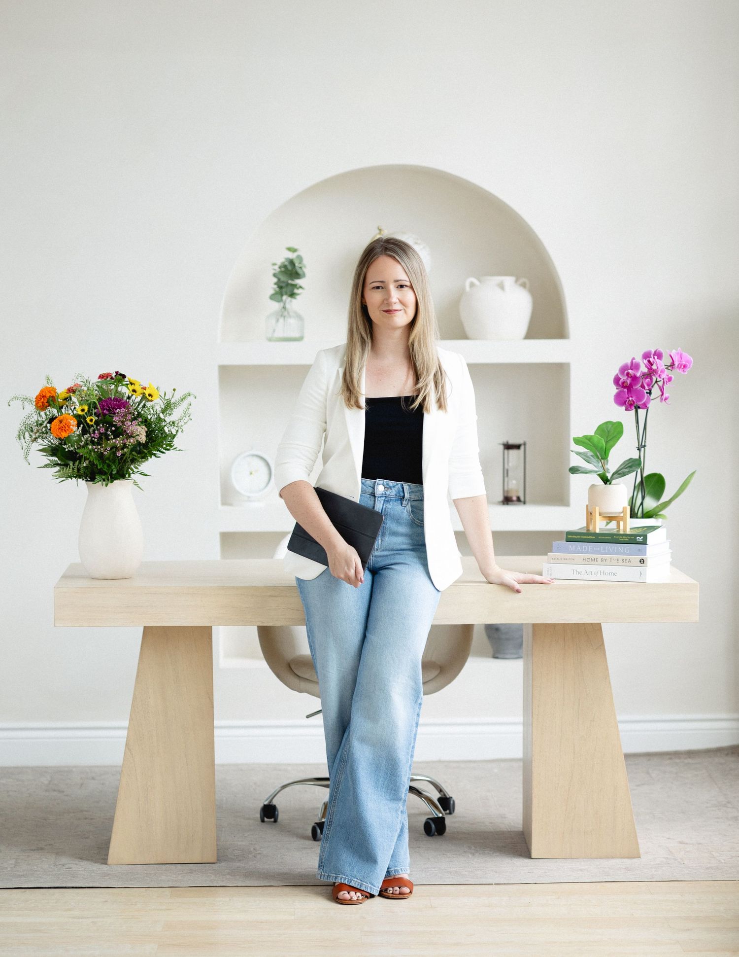 Branding photo of a therapist Nichole Cook standing by a desk with flowers, highlighting creativity and professionalism.