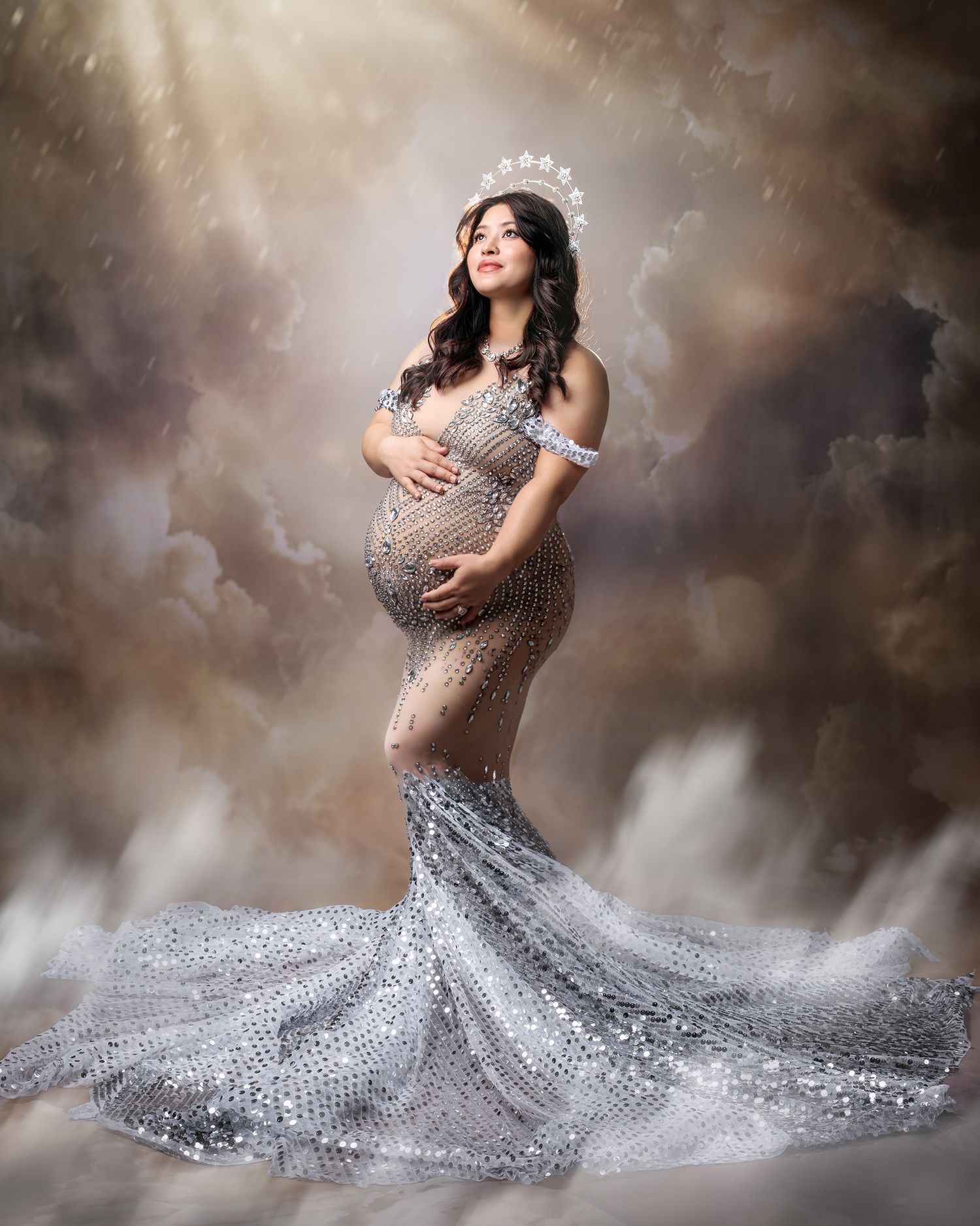 Metallic gold halter top and chiffon silk shirt, accentuating a pregnant woman's silhouette, against a scene of clouds and sunbeams.