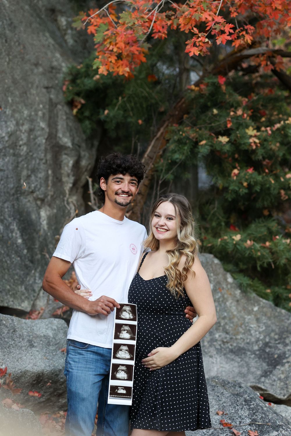 Couple announcing pregnancy near fall leaves