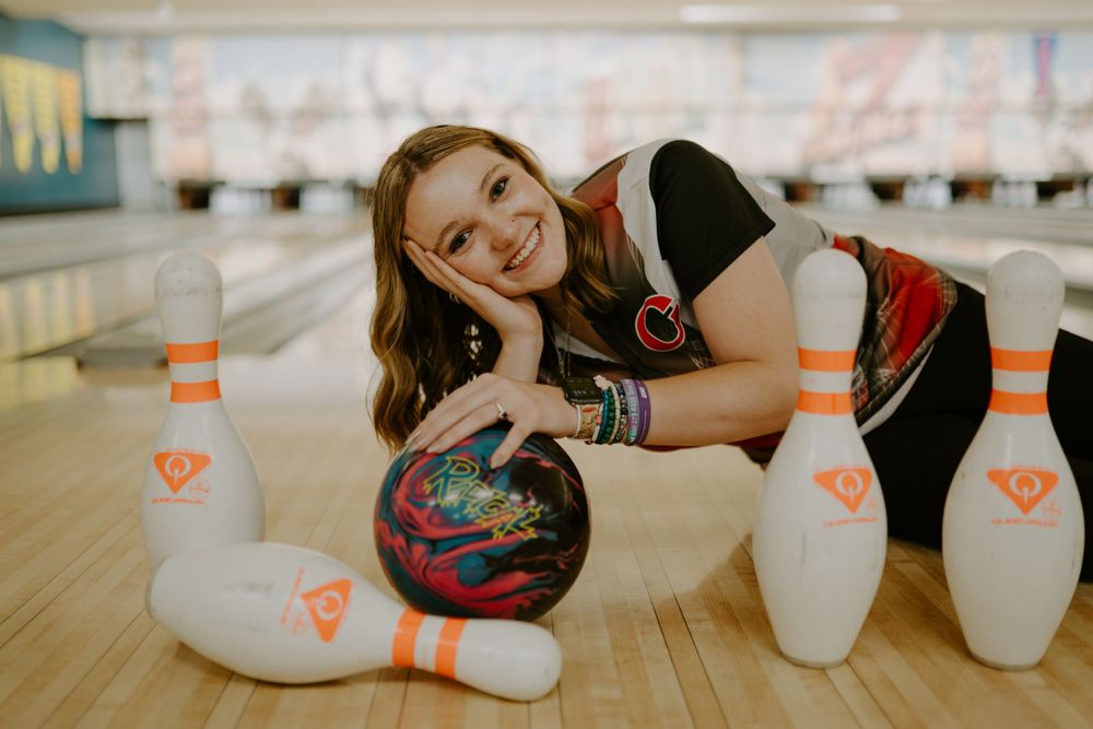Playful bowling alley photo session with white pins in background.