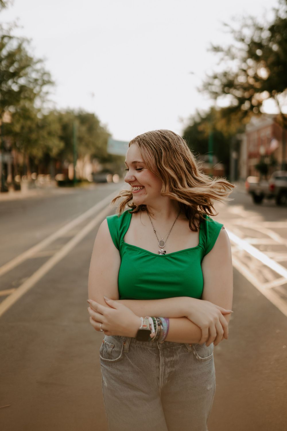 Casual street photography session featuring green top and denim on empty road.