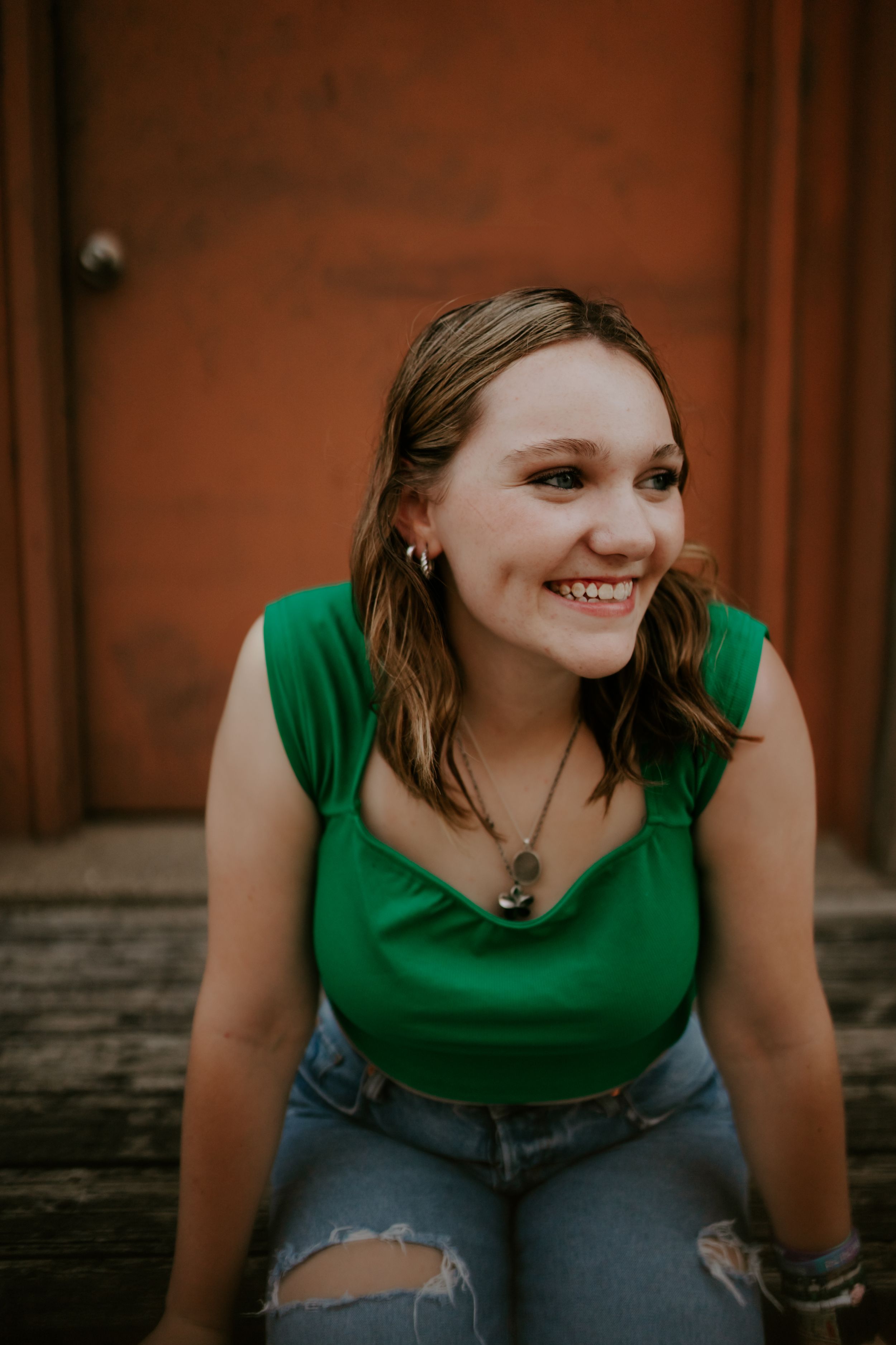 A series of casual portraits in a green top and ripped jeans against a brick wall background.