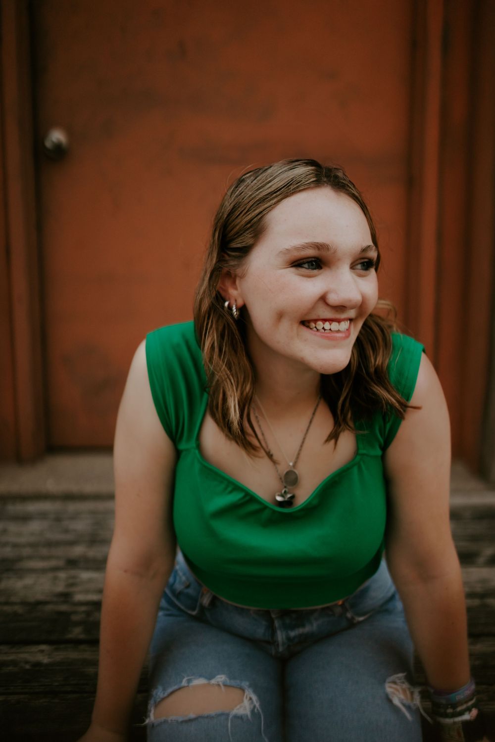 A series of casual portraits in a green top and ripped jeans against a brick wall background.