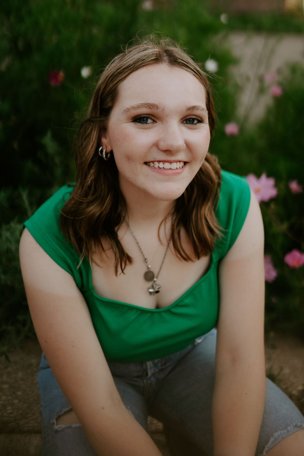 Outdoor portrait series with flowers featuring someone in an emerald green top and denim.