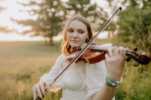 Sunset violin performance sequence in a white dress against golden hour lighting.