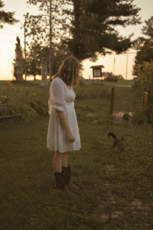 Dreamy sunset portrait session in a flowing white dress on grassy hillside.