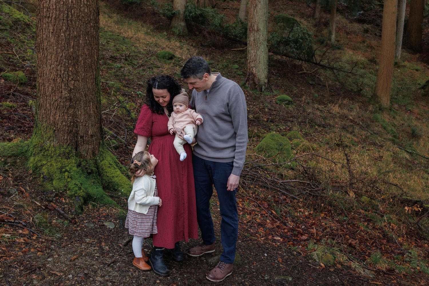 Family walking together on a wooded autumn trail holding hands on a crisp fall day.