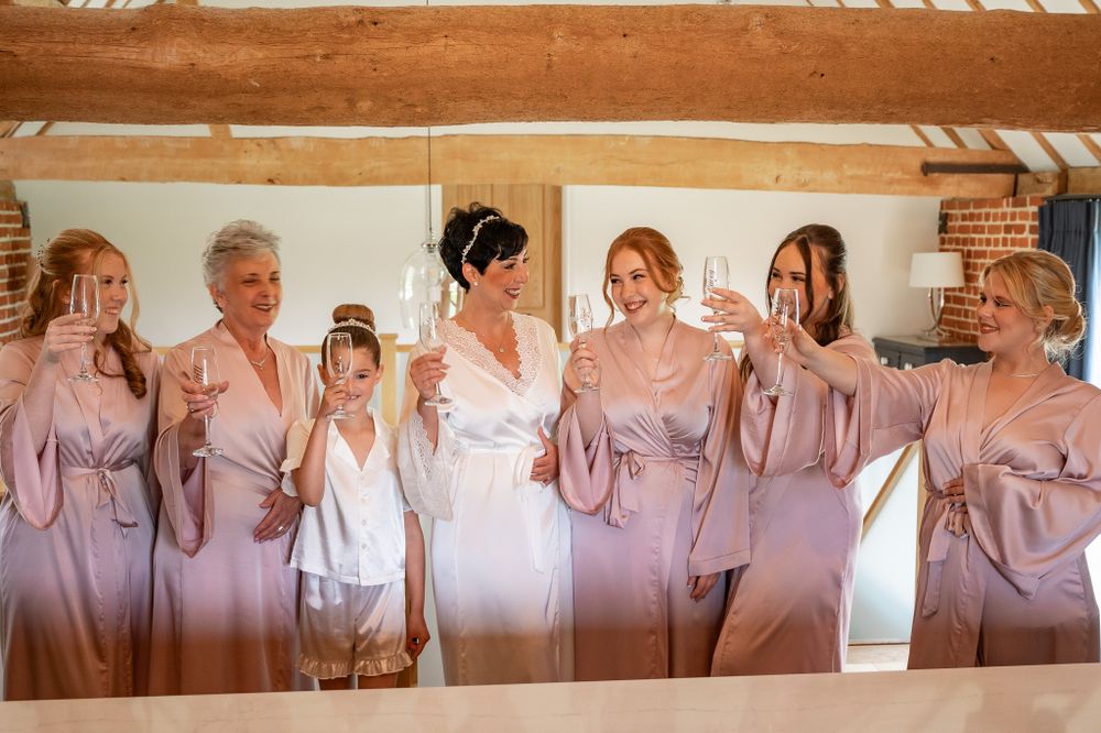 A bridal party in matching mauve satin robes poses together during wedding preparations.