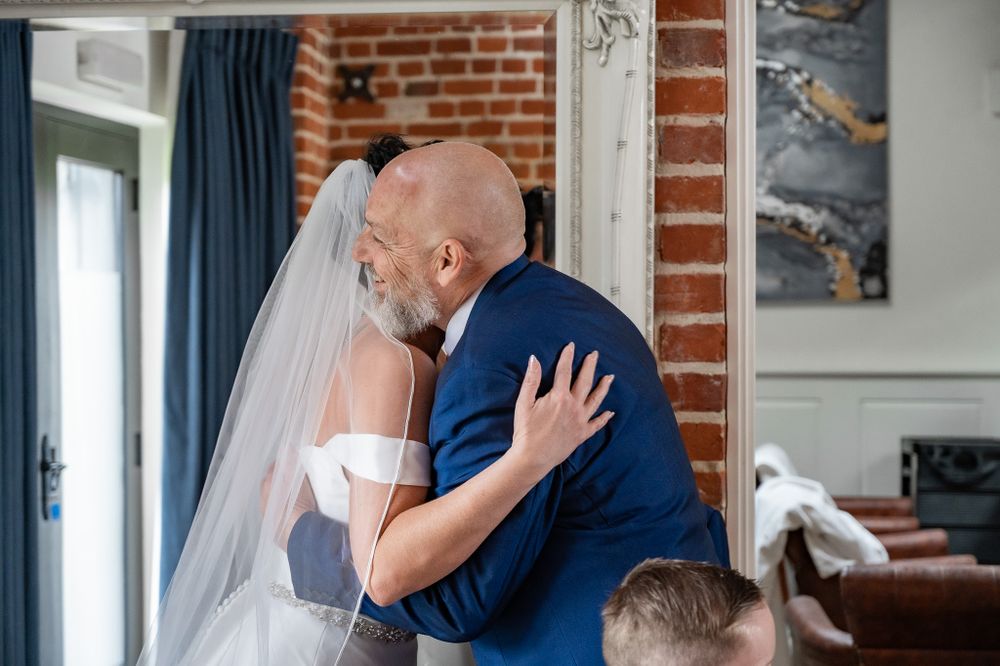 A tender wedding embrace between the couple in front of an exposed brick wall with navy curtains and artwork.