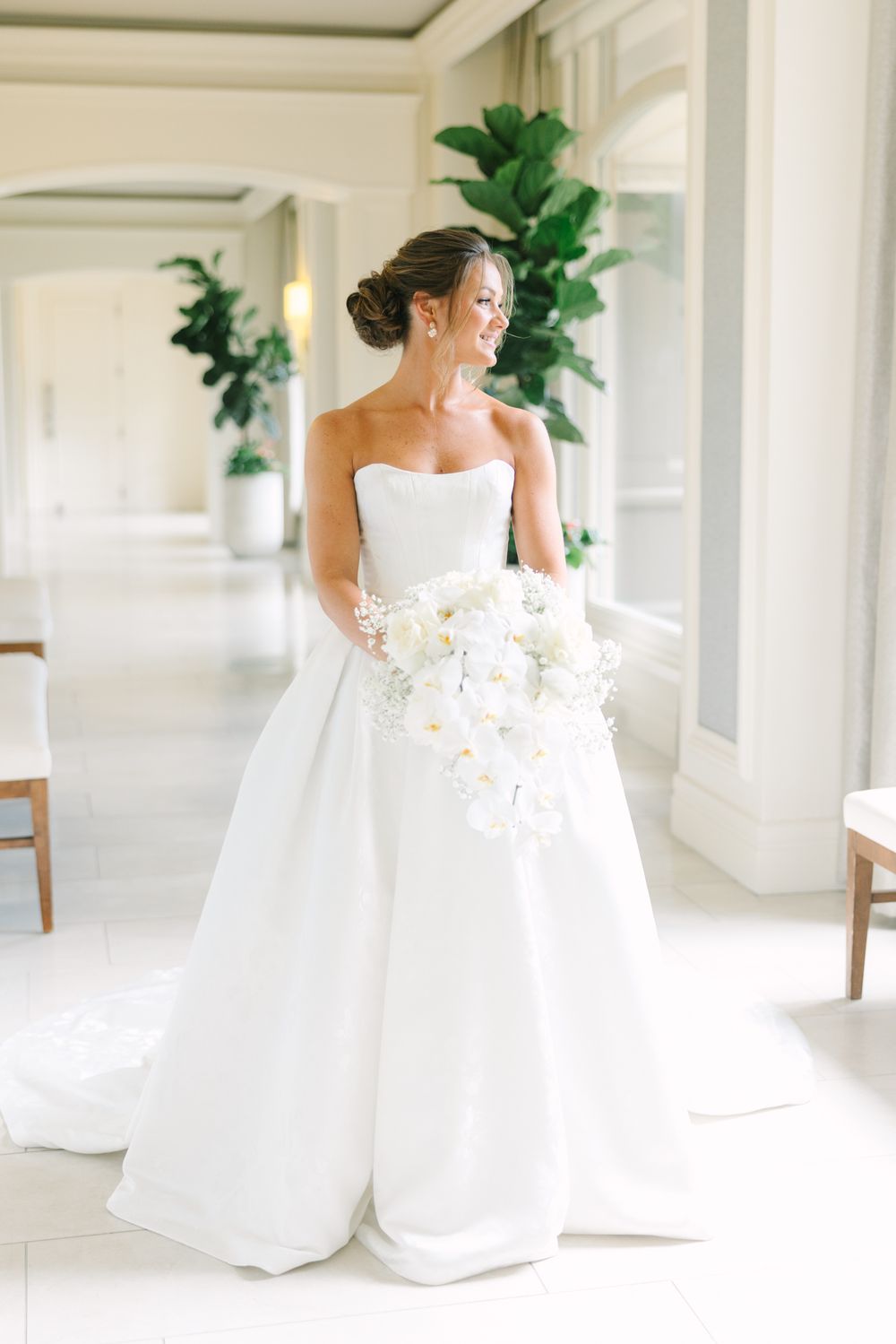 bride in gown with bouquet in hallway