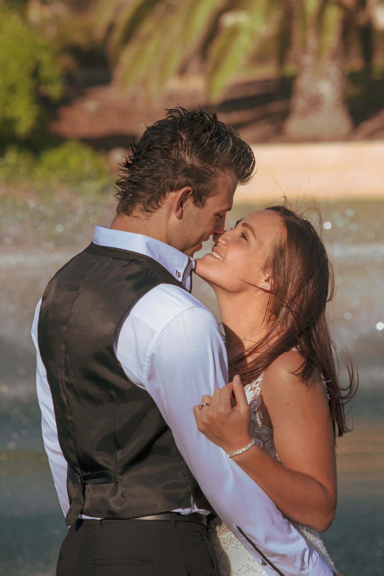 Romantic moment captured between couple in formal attire near beach.