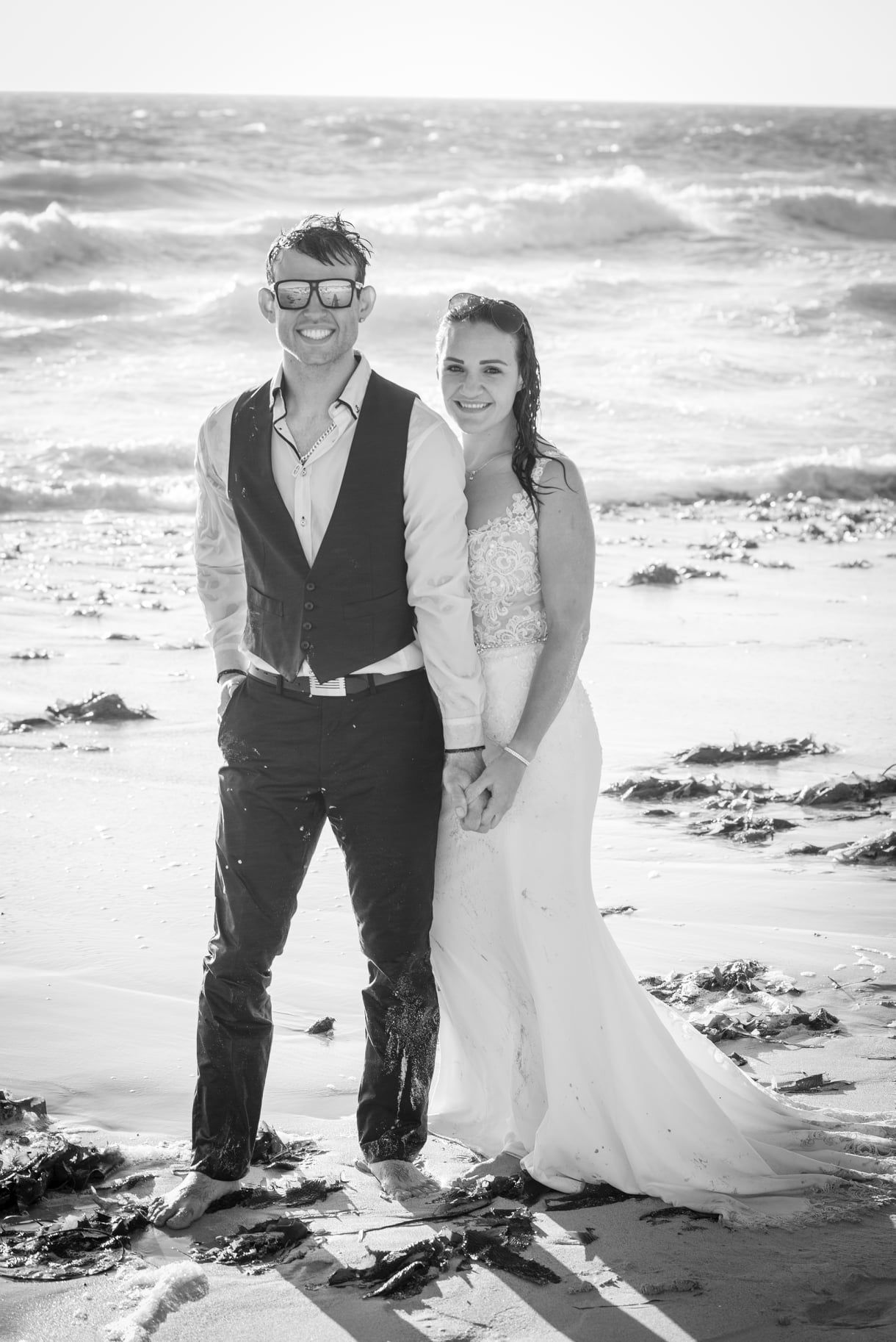 Black and white beach portrait of couple in wedding attire.