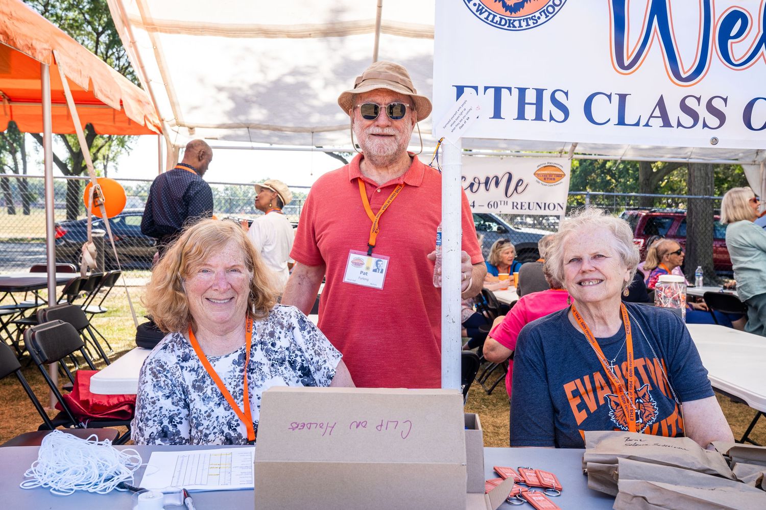 Group of seniors at outdoor class reunion event with registration table.