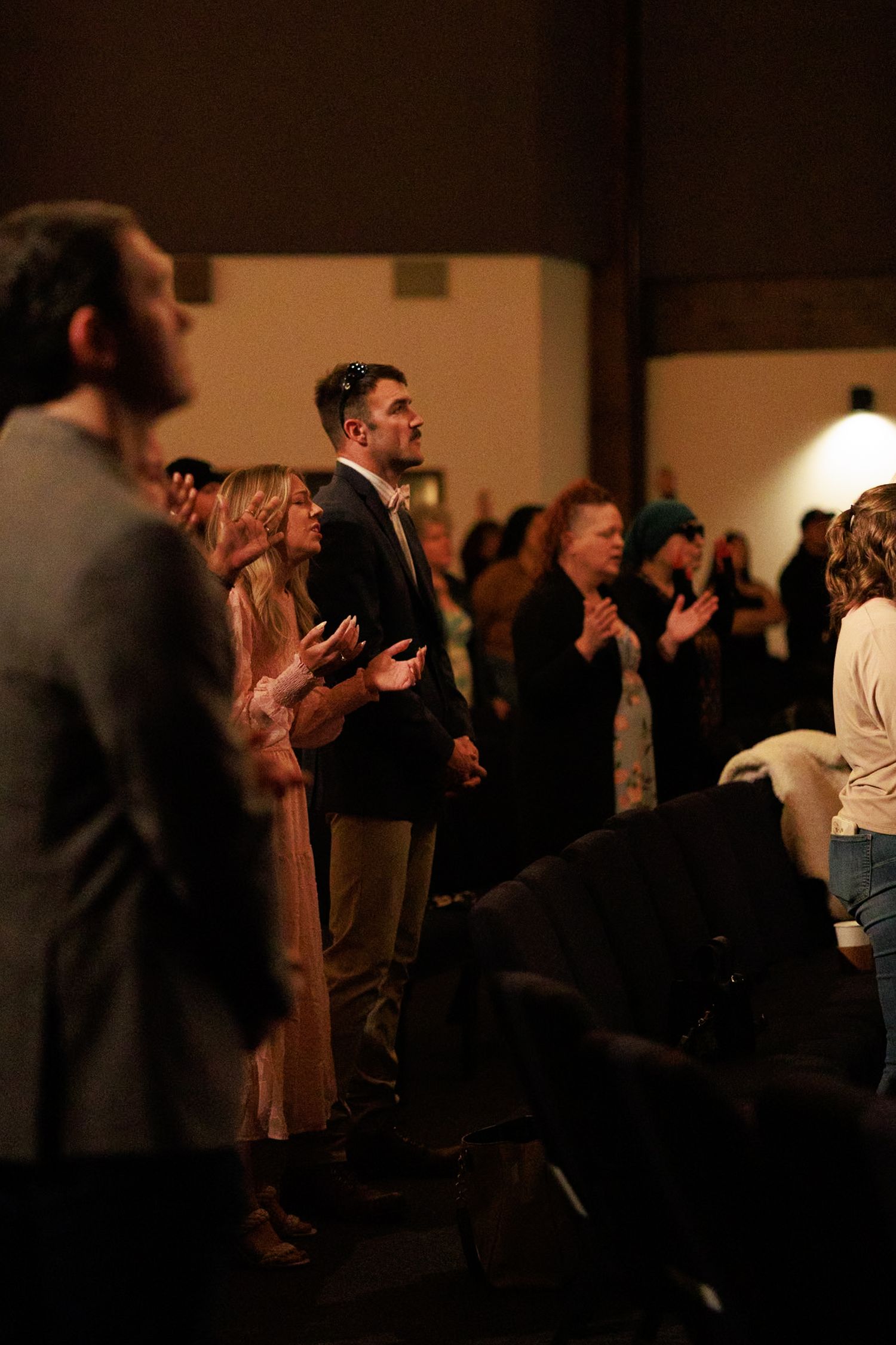 Crowd of people standing in a dimly lit room during an event.