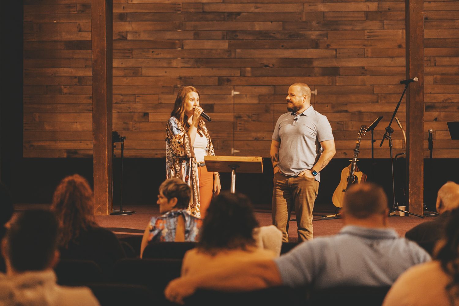 People gathered for a presentation in a modern church space with wooden wall panels.