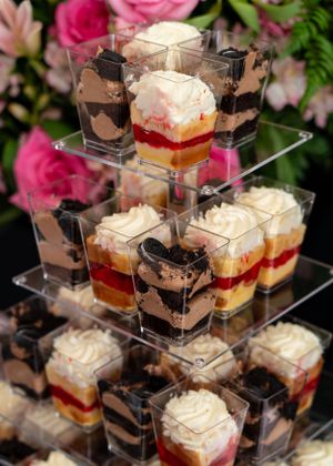 Elegant dessert display with layered chocolate and strawberry trifle cups arranged on a tiered acrylic stand.