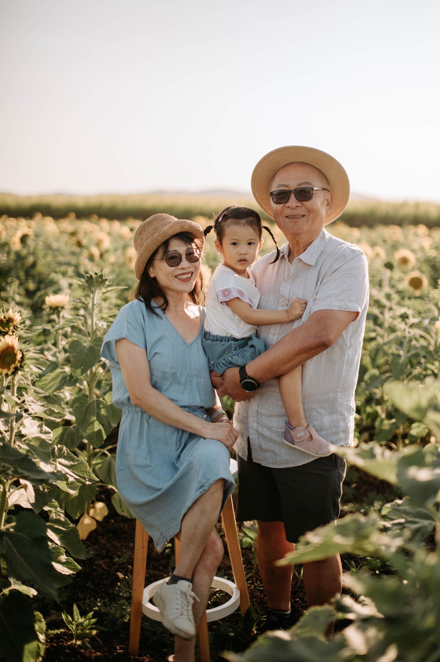 Family portrait in a sunflower field during golden hour.