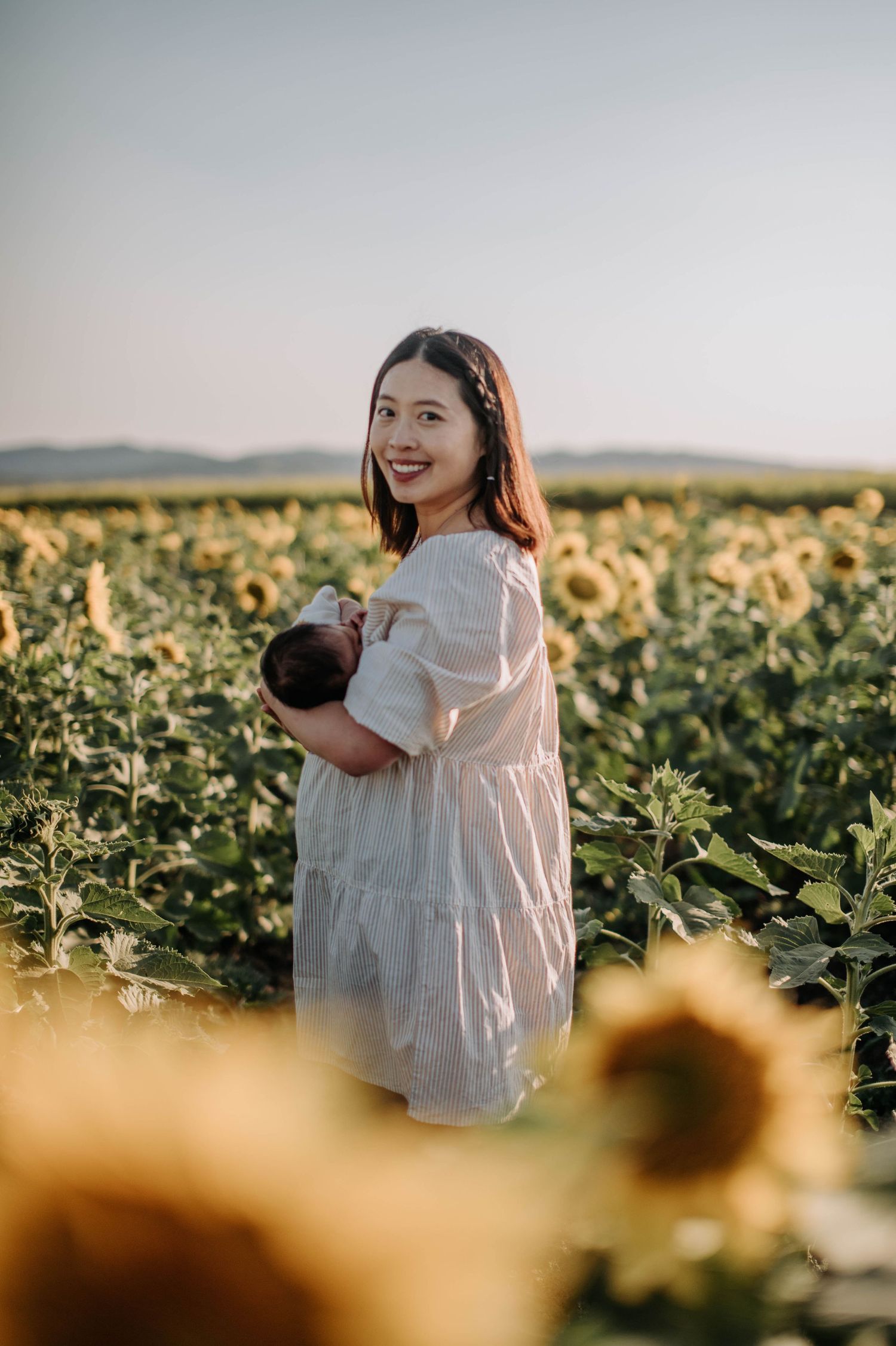 A sunny day portrait in a sunflower field with a white summer dress.