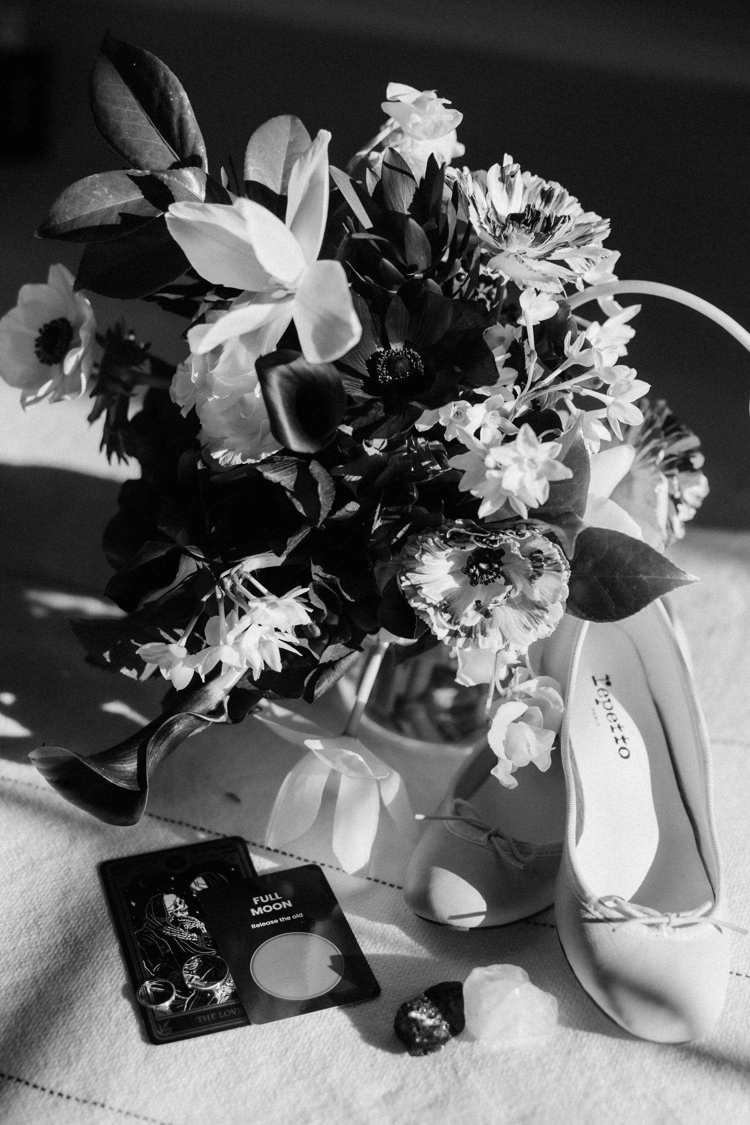 Black and white close-up of a romantic wedding moment showing lace sleeve details and delicate veil.