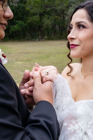Close-up sequence showing a couple's tender moment during their wedding ceremony with focus on hands and white lace dress.