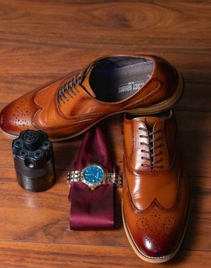 Brown leather wingtip oxford dress shoes displayed in sequence on wooden surface.