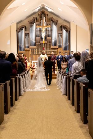 Church wedding ceremony with guests seated in wooden pews and a large pipe organ at the altar.