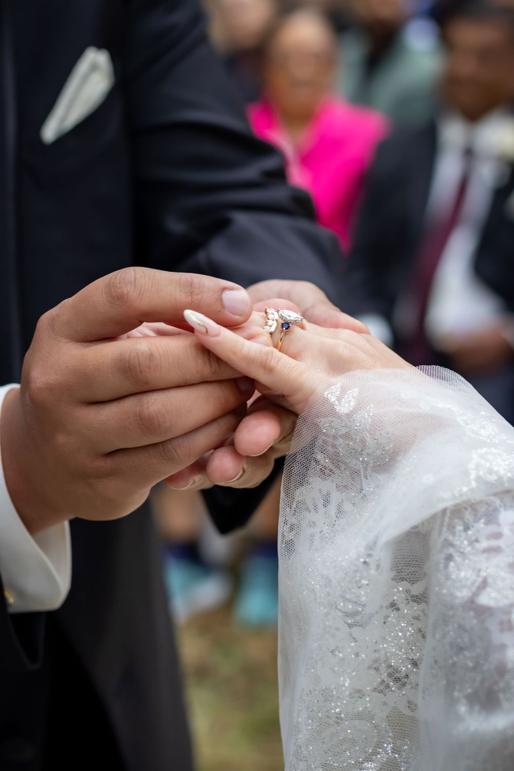 Close-up sequence of hands exchanging rings during a wedding ceremony with white lace details.