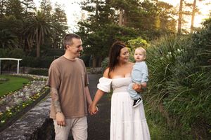 Mother holding her toddle and holding her husbands hand in a Newcastle NSW garden during a 1st birthday milestone photoshoot