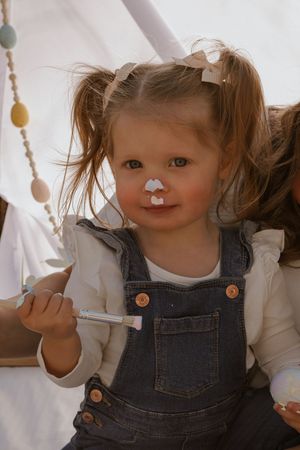 Playful scene with paint-covered faces and denim overalls during art time.
