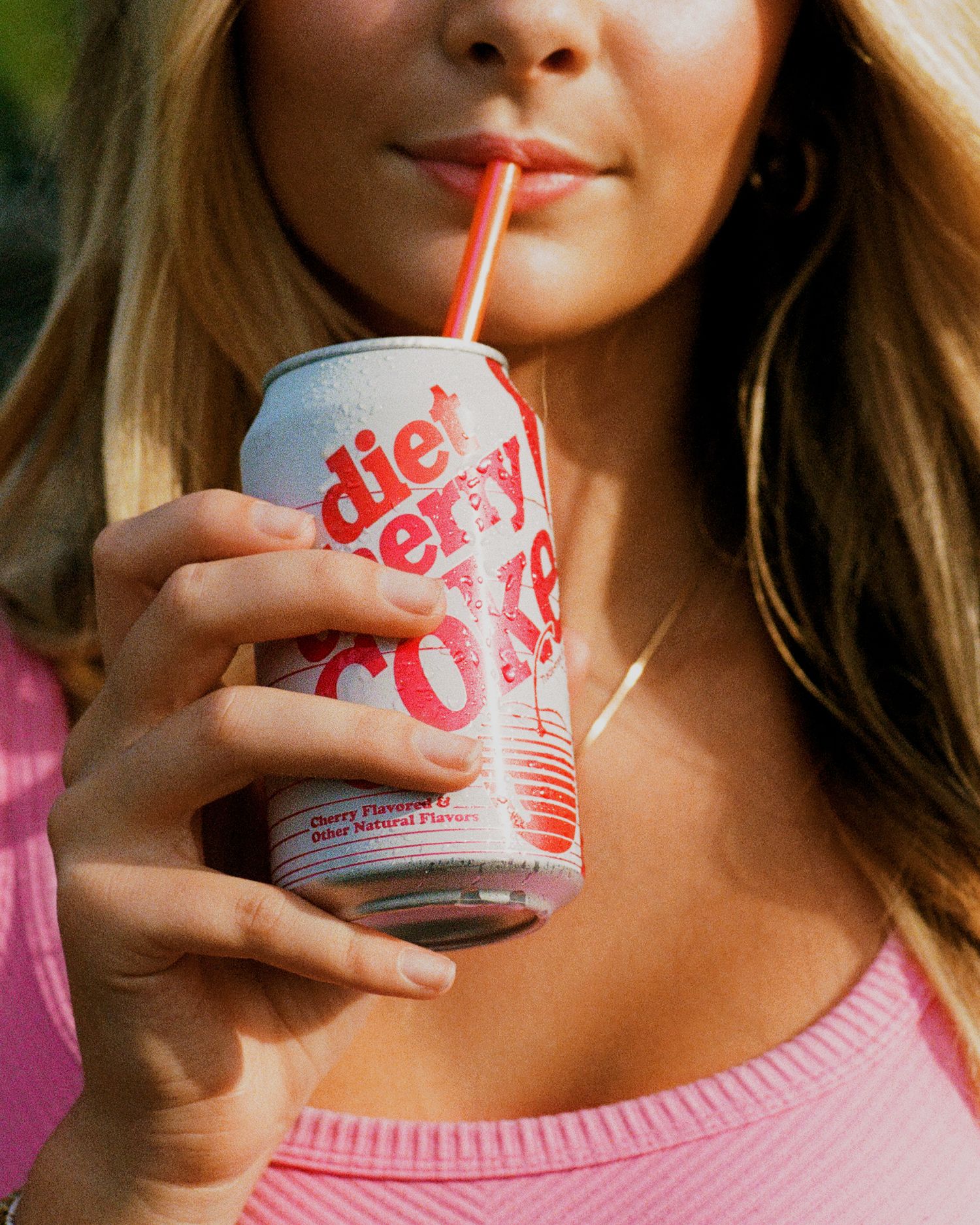 A series of photos showing someone drinking Diet Cherry Coke through a straw from a disposable can
