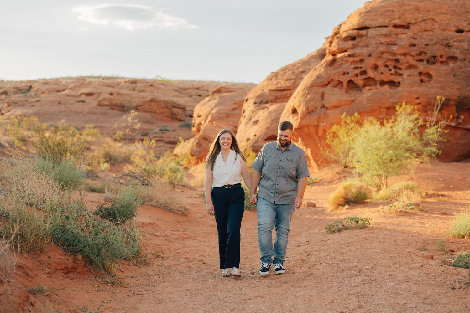 Family poses together against stunning red rock formations in a desert landscape during sunset.
