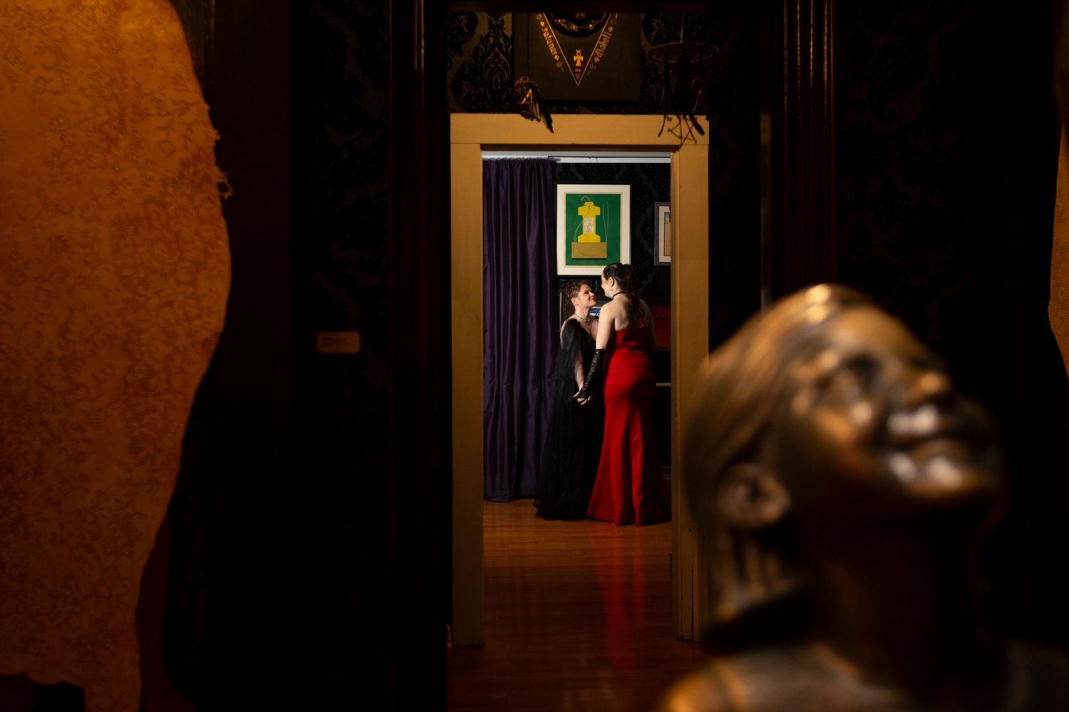 Two brides embrace in the Satanic Temple art museum after they say "I do."
