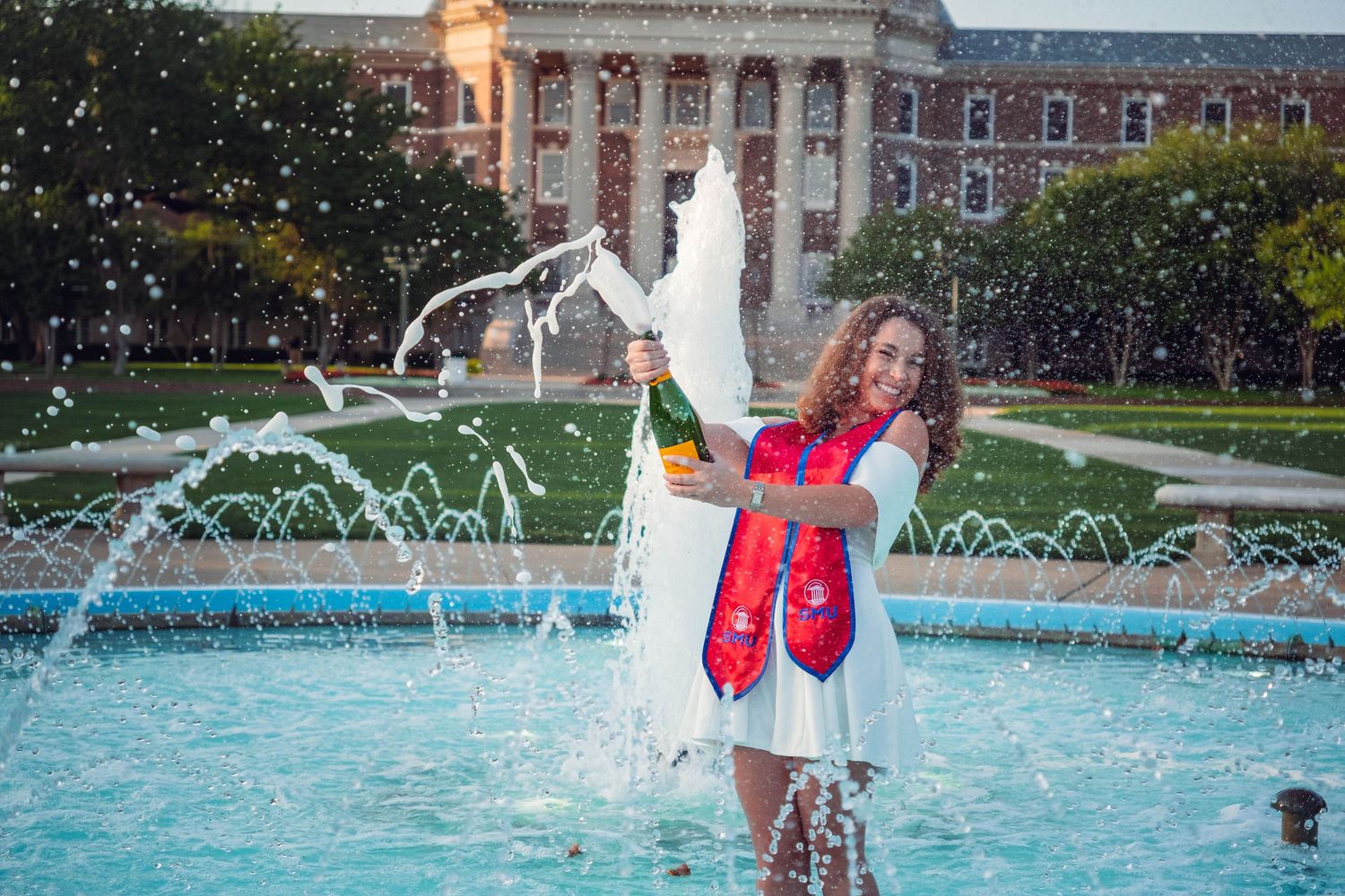 Playful photos by a fountain with water splashing in the background.