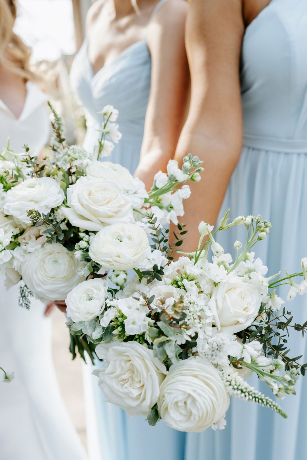 Elegant white rose and baby's breath bouquets held against light blue bridesmaid dresses.