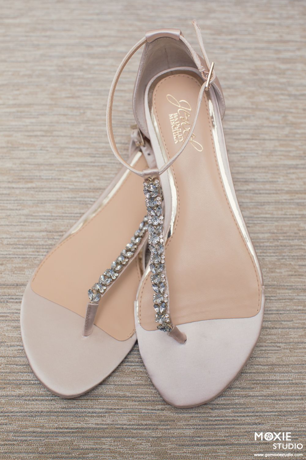 Elegant white bridal sandals with crystal embellishments on T-strap design shown from multiple angles on gray surface.