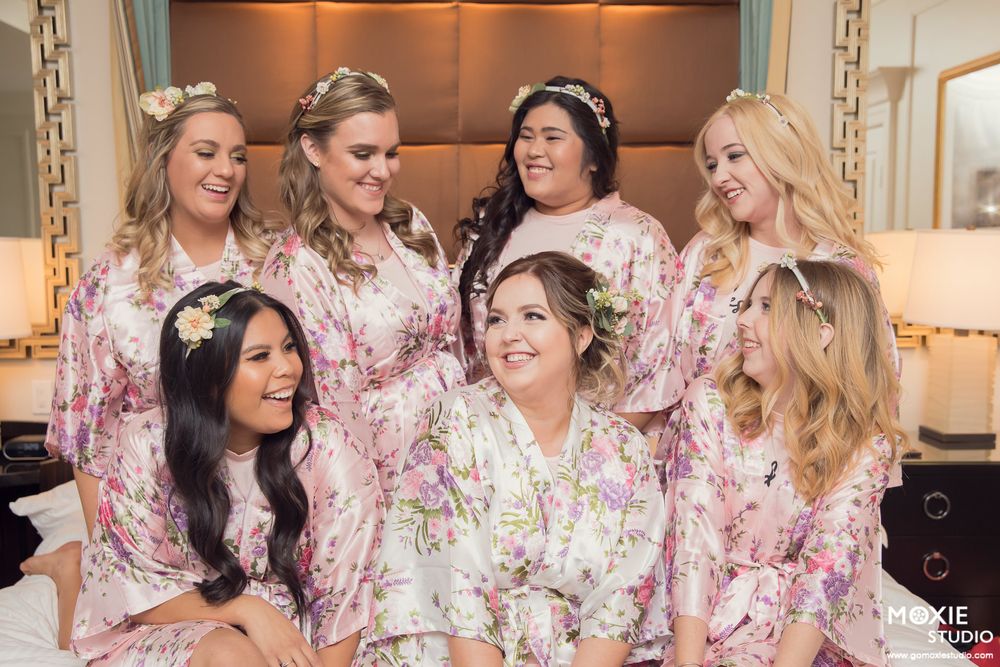 A group wearing matching floral robes gathers together in a bridal preparation setting.