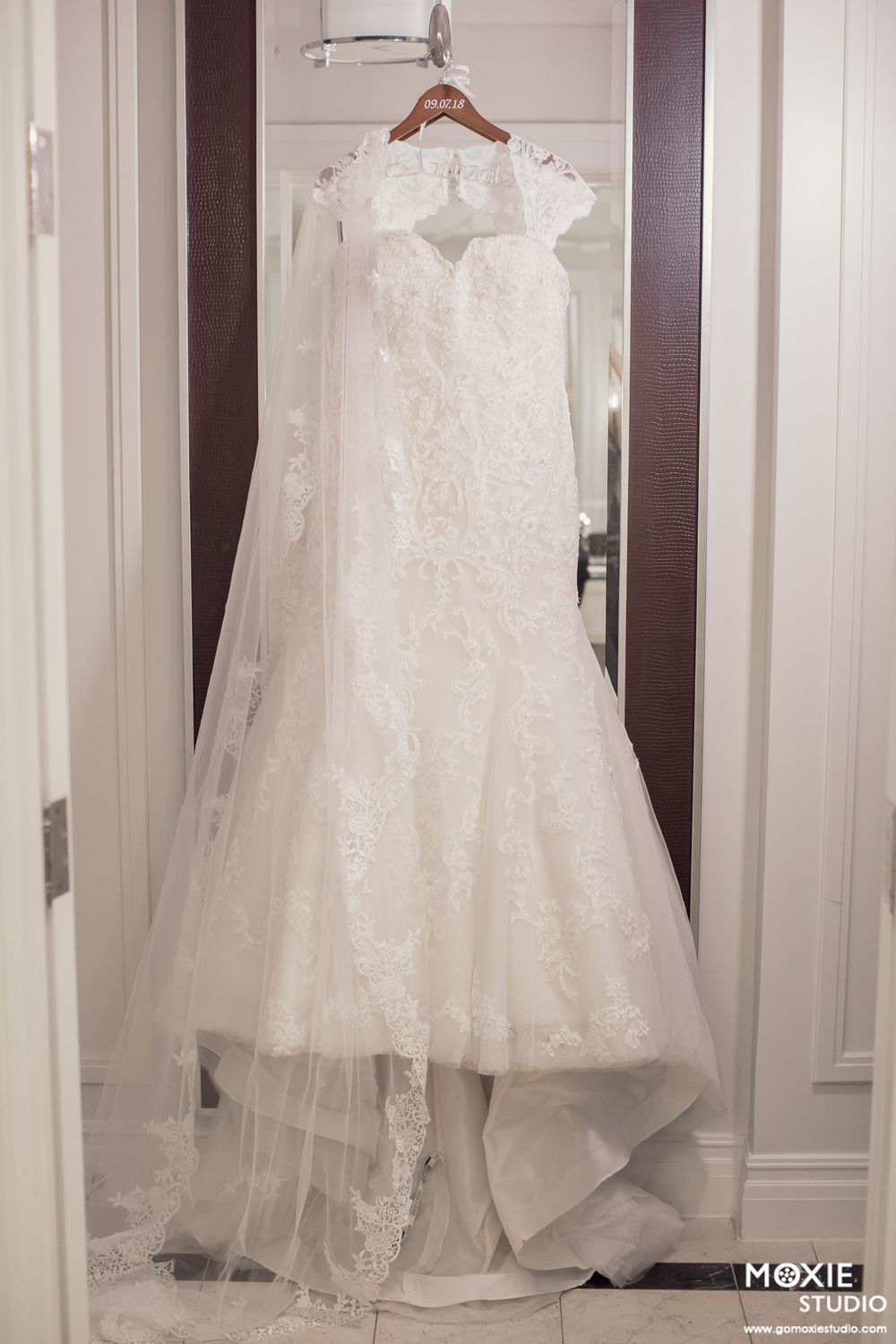White wedding dresses and veils hang on display in an elegant bridal boutique fitting room.