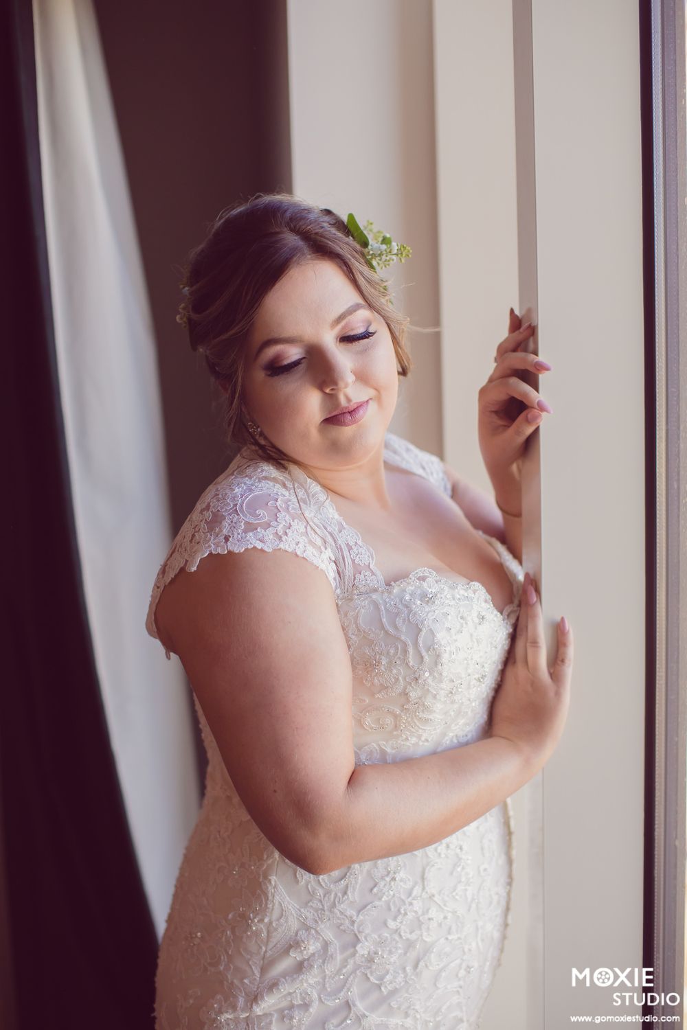 A bride in a lace wedding dress poses elegantly by a window in a series of connected portrait shots.