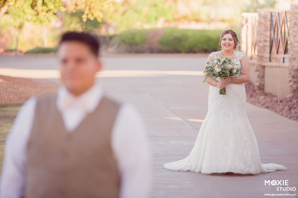Bride and groom share romantic moments in an outdoor desert venue with soft pink sunset lighting.