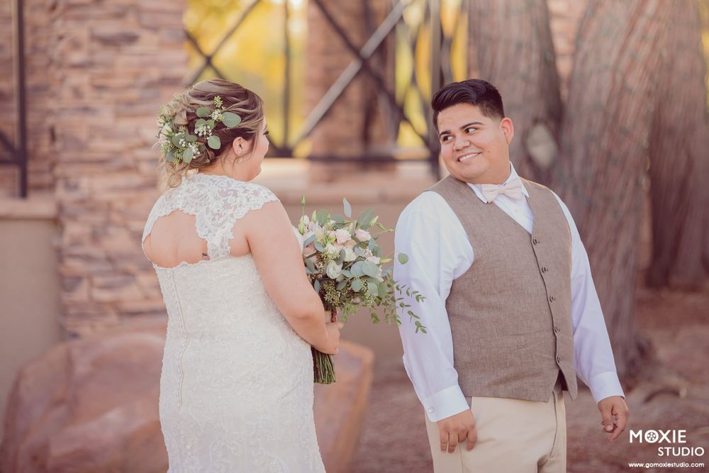Couple sharing a tender moment during their wedding at sunset against a stone wall backdrop.