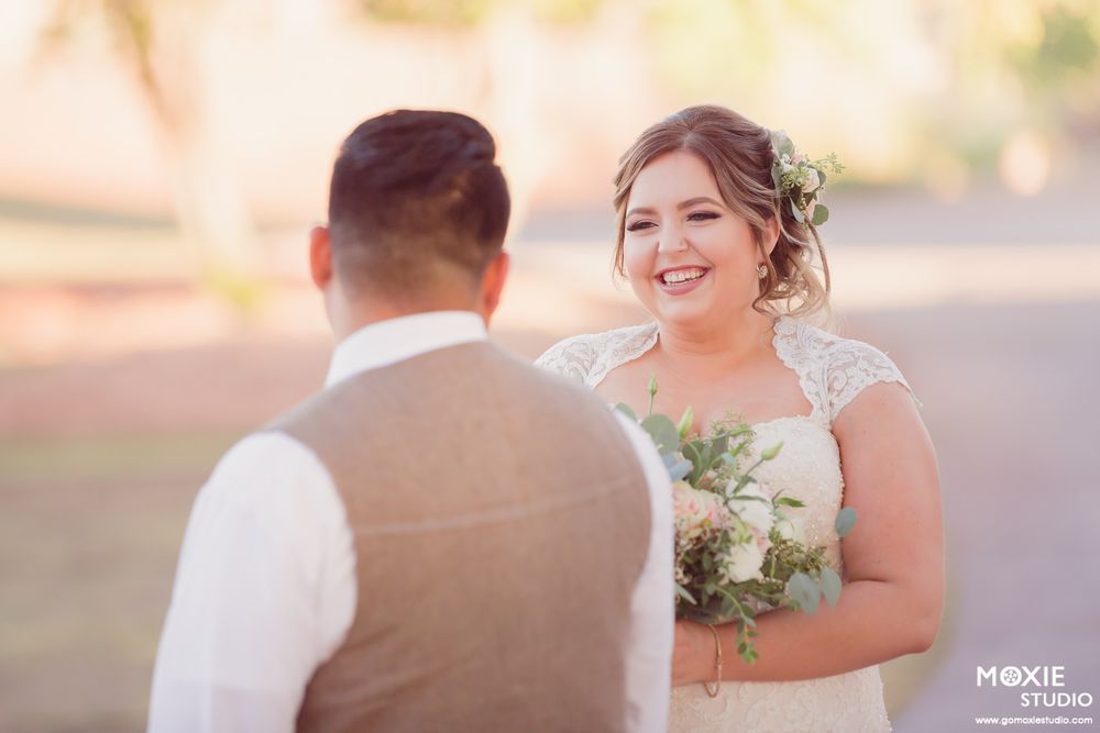Newlyweds share a romantic moment during golden hour with soft lighting and stone architecture.