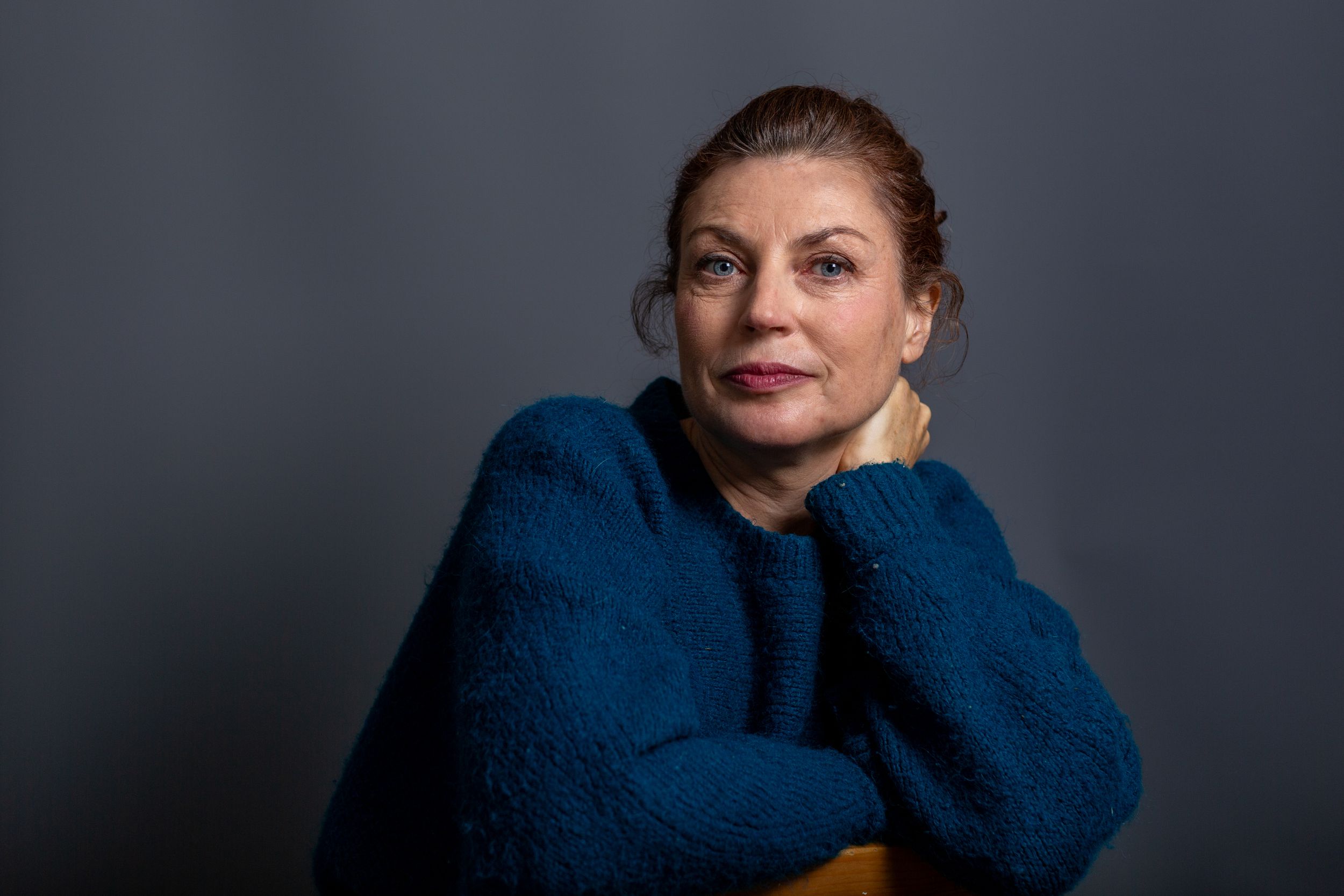 A sequence of portrait photos showing someone wearing a blue sweater against a dark background.