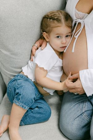 A series of intimate breastfeeding photos showing a baby in denim shorts nursing while lying down on a gray surface.